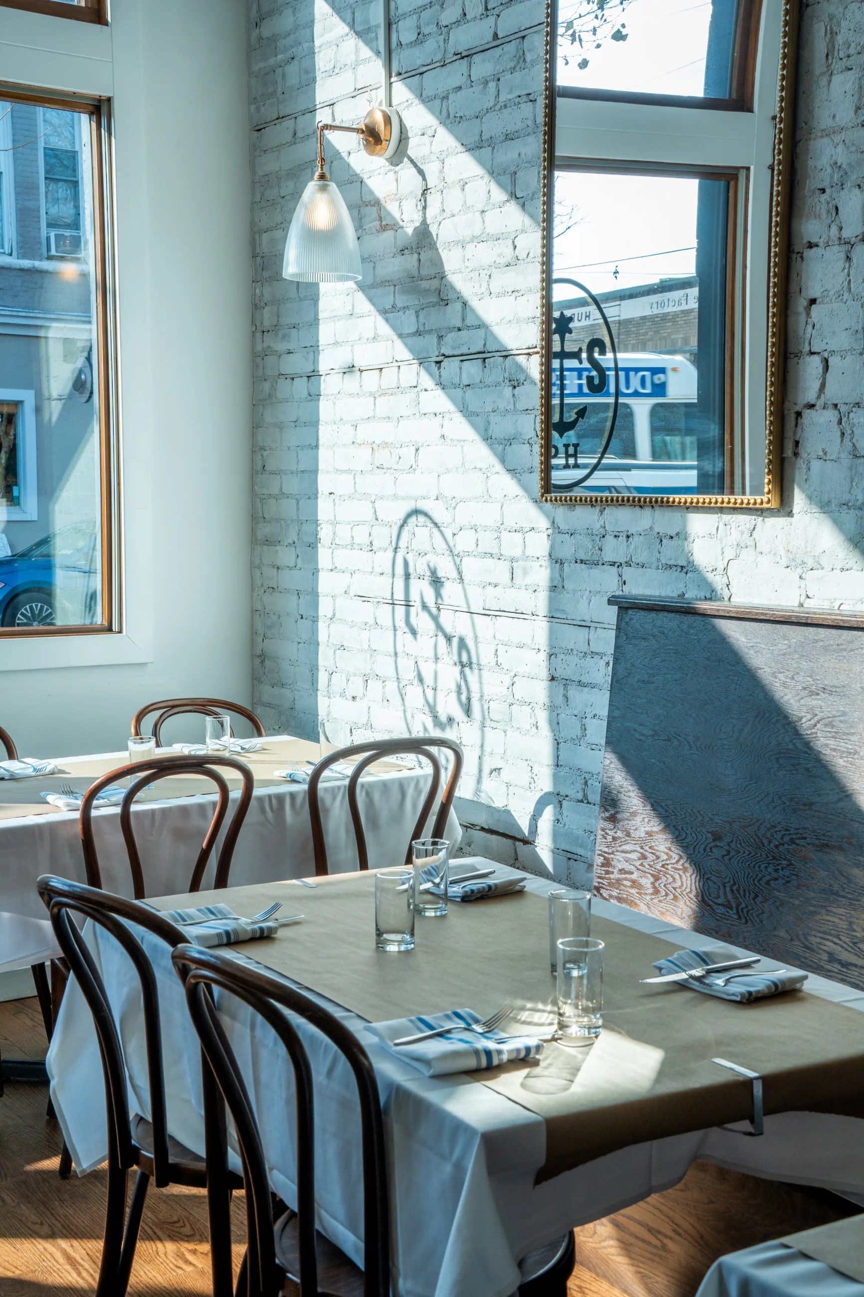 A sunlit corner table by the window against whitewashed brick.